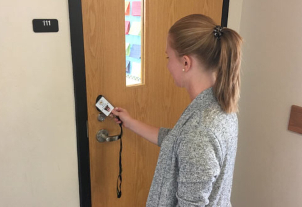 Teacher using new key card to open door. 